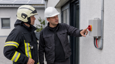 Feuerwehrmann und Elektriker prüfen einen PV-Trennschalter am Gebäude [Bildinhalt mit KI erstellt]