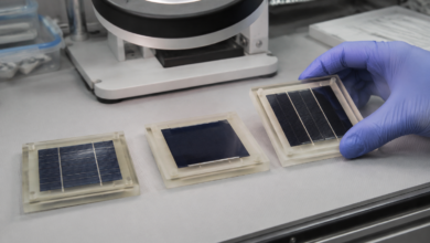 Solarzellen-Proben und eine Lupenleuchte auf einem aufgeräumten Laborarbeitstisch. [Bildinhalt mit KI erstellt]