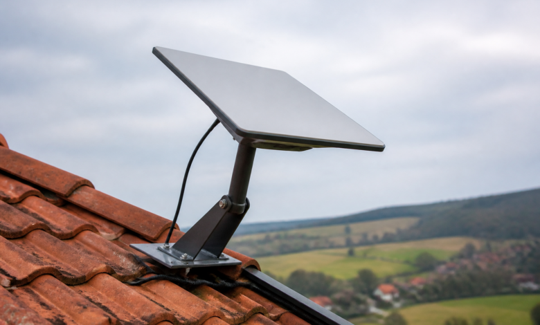 Flache Satelliteninternet-Antenne auf einer Halterung am Dach eines ländlichen Wohnhauses. [Bildinhalt mit KI erstellt]