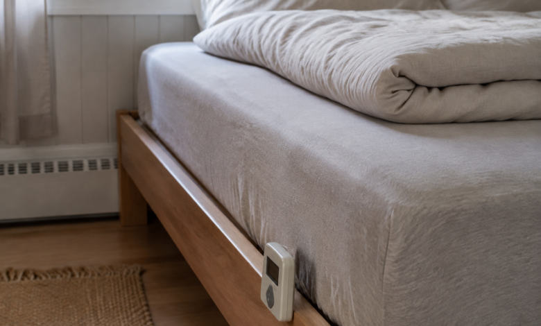 Wasserbett mit textilem Bezug und einem kleinen kabelgebundenen Heizregler am Bettrahmen. [Bildinhalt mit KI erstellt]